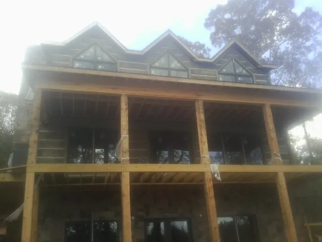 Dormers and porch framing on a large log home under construction — Roof Coating work by our crew in Englewood